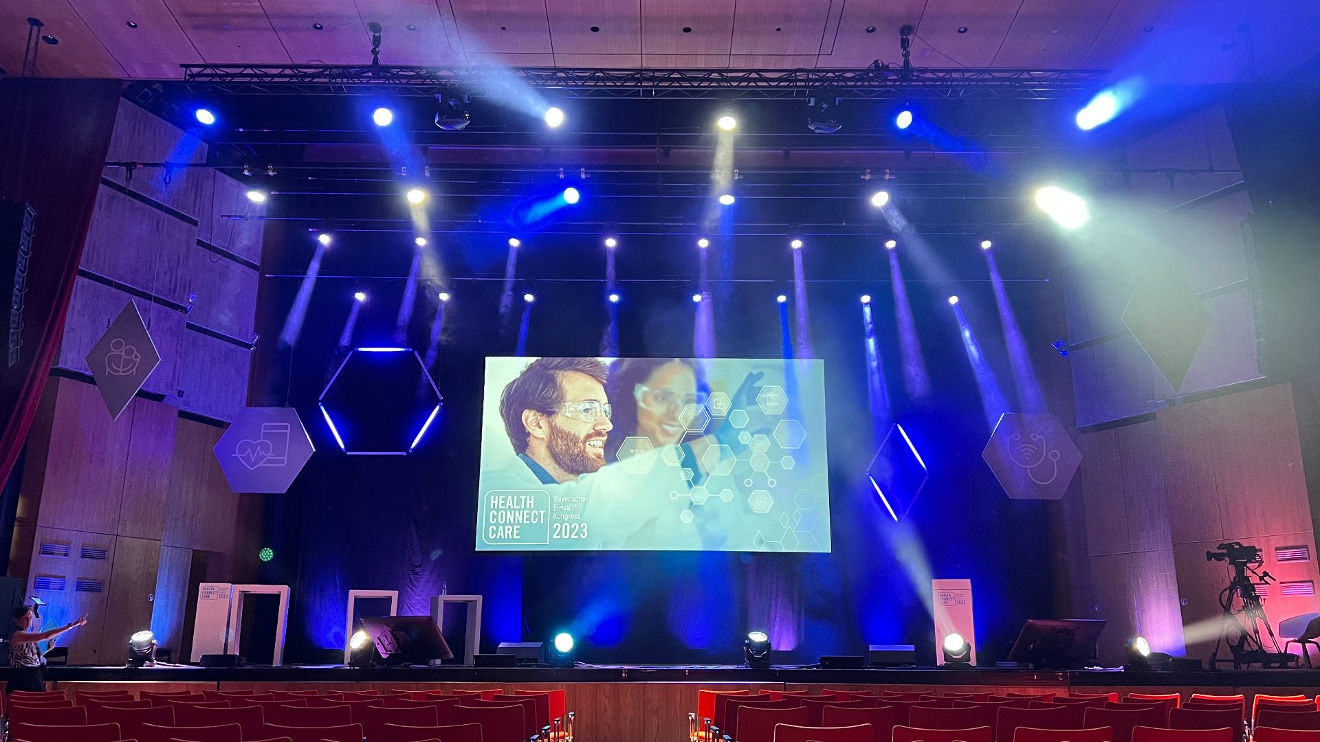 Kongresssaal mit großer Bühnenleinwand und blauem Licht