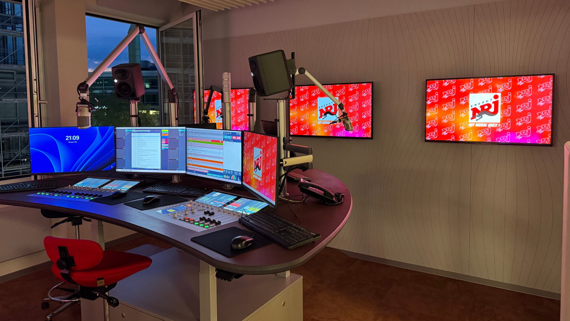 Rundfunkstudio mit mehreren Bildschirmen und Mischpult im Senderdesign